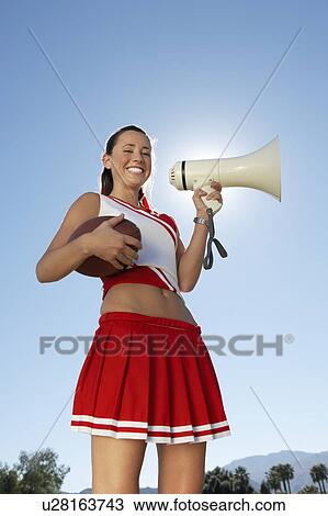Cheerleader Holding Football and Megaphone, low angle view, portrait, (portrait), (low angle view) View Large Photo Image Stock Image - Cheerleader Holding Football and Megaphone, low angle view, portrait, (portrait), (low angle view). Fotosearch