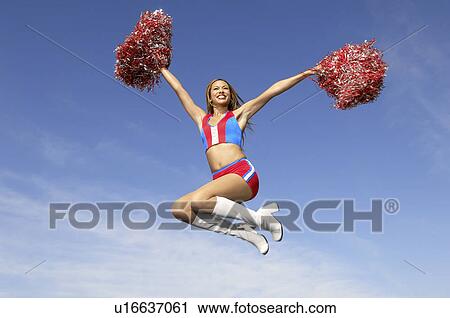 Cheerleader in jumping with pom poms raised, mid air View Large Photo Image Stock Image - Cheerleader in jumping with pom poms raised, mid air. Fotosearch