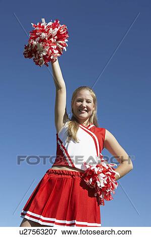 Stock Photo - Cheerleader rising pom-pom in air, low angle view, portrait, (portrait), (low angle view). Fotosearch