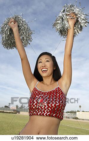 Picture - Cheerleader with pom poms raised. Fotosearch