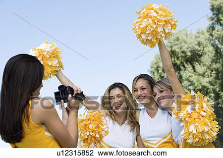 Stock Image - Cheerleaders video taping friends. Fotosearch