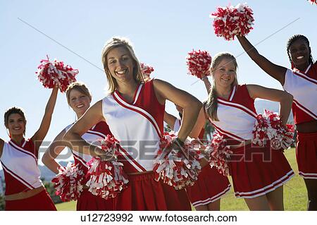 Stock Image - Cheerleading squad standing in formation on field, portrait, (portrait). Fotosearch