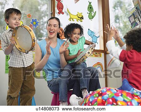 Stock Image - Children with teacher playing music in classroom. Fotosearch