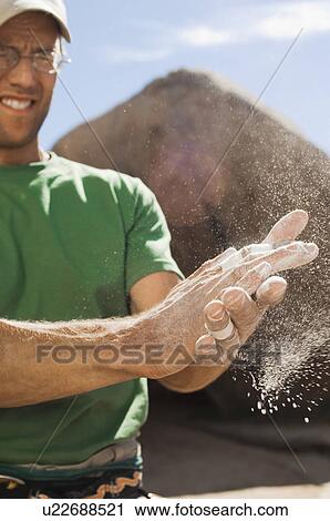 Stock Image - Climber Rubbing Chalk on Hands. Fotosearch