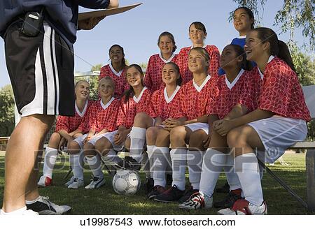 Stock Image - Coach talking to girls' soccer team (13-17). Fotosearch