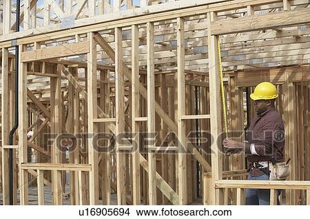 Construction Worker measuring boards on Site View Large Photo Image Picture - Construction Worker measuring boards on Site. Fotosearch