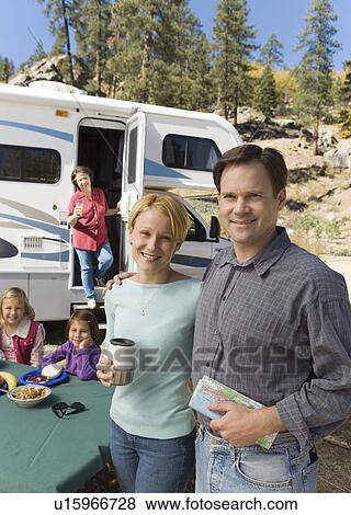 Stock Photo - Couple and family outside RV in campground. Fotosearch