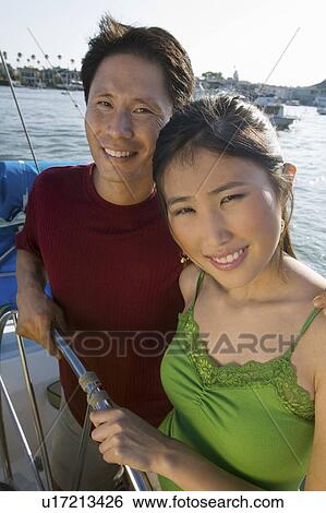 Stock Photograph - Couple at helm on boat, (portrait). Fotosearch