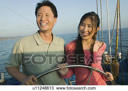 Couple at steering wheel of sailboat, smiling View Large Photo Image Stock Image - Couple at steering wheel of sailboat, smiling. Fotosearch
