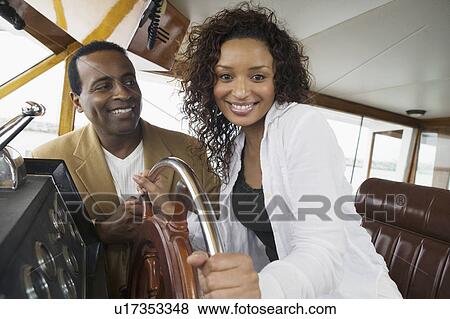 Couple at steering wheel on yacht, (portrait) View Large Photo Image Stock Photo - Couple at steering wheel on yacht, (portrait). Fotosearch