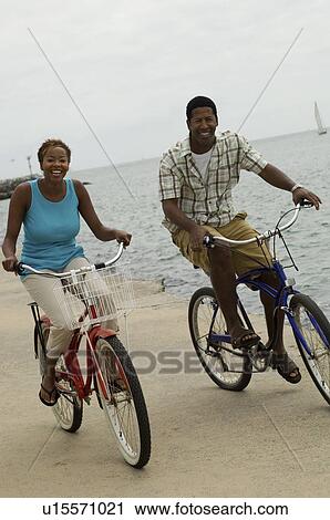Couple cycling on beach, smiling View Large Photo Image Stock Image - Couple cycling on beach, smiling. Fotosearch