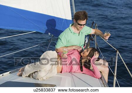 Stock Photo - Couple dinking white wine on sailboat. Fotosearch