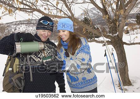 Couple drinking out of thermos in snow covered field View Large Photo Image Stock Image - Couple drinking out of thermos in snow covered field. Fotosearch
