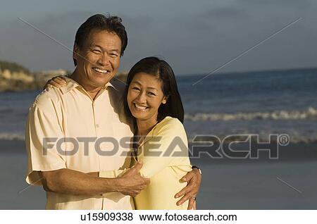 Stock Photo - Couple embracing on beach, (portrait). Fotosearch