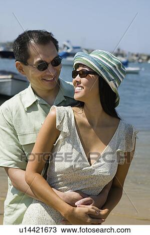 Stock Image - Couple embracing on beach. Fotosearch