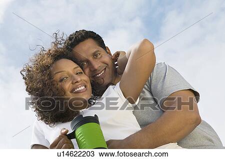 Couple embracing outdoors, (portrait), (low angle view) View Large Photo Image Stock Image - Couple embracing outdoors, (portrait), (low angle view). Fotosearch
