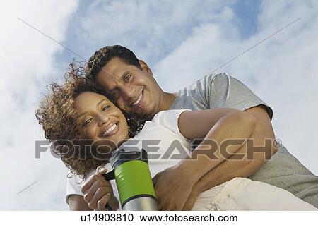 Couple embracing outdoors, (portrait), (low angle view) View Large Photo Image Stock Image - Couple embracing outdoors, (portrait), (low angle view). Fotosearch