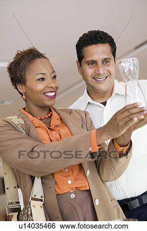 Stock Photograph - Couple Examining Glass Vase in furniture store. Fotosearch