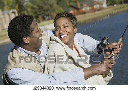 Stock Image - Couple fly fishing together, smiling. Fotosearch