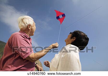 Couple flying kite outdoors, (low angle view) View Large Photo Image Stock Image - Couple flying kite outdoors, (low angle view). Fotosearch