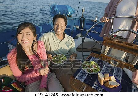 Stock Photography - Couple having lunch on sailboat, (portrait). Fotosearch