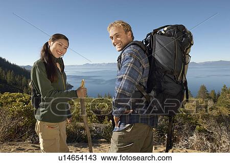 Stock Image - Couple hiking at coast, (portrait). Fotosearch