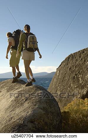 Couple hiking on boulders at coast View Large Photo Image Picture - Couple hiking on boulders at coast. Fotosearch