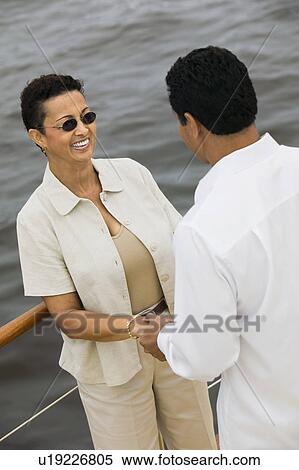 Stock Photography - Couple holding hands on yacht, (elevated view). Fotosearch