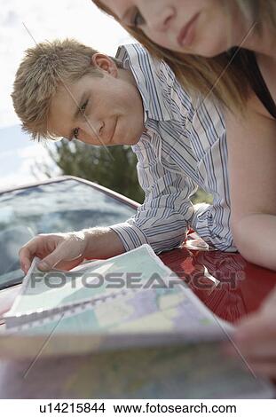 Couple leaning on car looking at map View Large Photo Image Picture - Couple leaning on car looking at map. Fotosearch