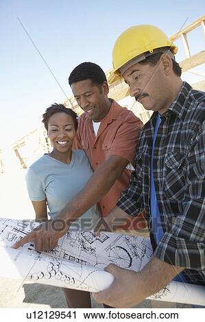 Couple looking at blue prints with builder View Large Photo Image Stock Image - Couple looking at blue prints with builder. Fotosearch