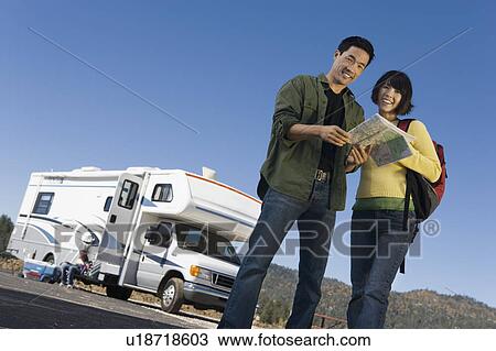 Stock Image - Couple looking at map outside RV. Fotosearch