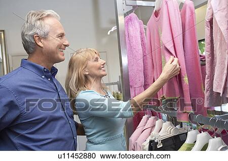 Couple looking at sweaters hanging in clothing shop on Shopping Trip View Large Photo Image Stock Image - Couple looking at sweaters hanging in clothing shop on Shopping Trip. Fotosearch