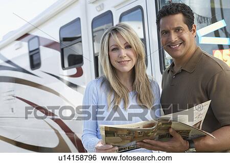 Stock Photograph - Couple looking through RV brochure, portrait. Fotosearch