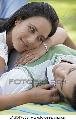 Couple lying down together on blanket in park View Large Photo Image Stock Photo - Couple lying down together on blanket in park. Fotosearch