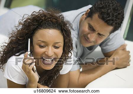 Picture - Couple lying on yacht, woman talking on mobile phone. Fotosearch