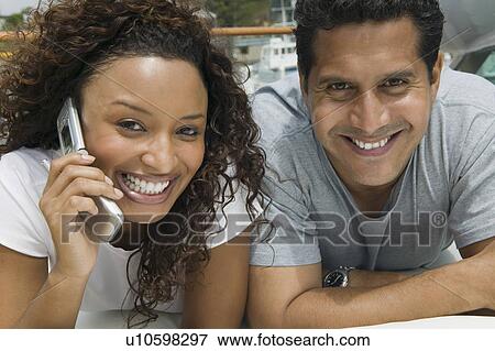 Stock Photo - Couple lying on yacht, woman talking on mobile phone, (close-up), (portrait). Fotosearch