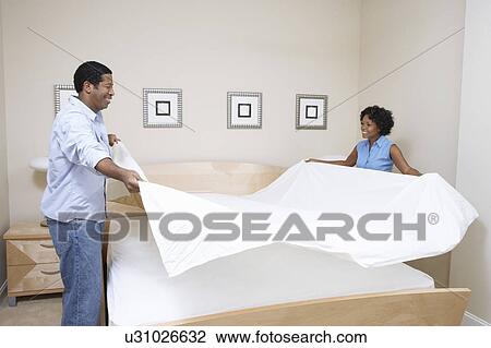 Couple making bed together View Large Photo Image Stock Image - Couple making bed together. Fotosearch