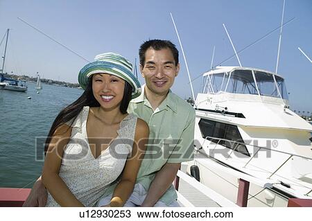 Stock Image - Couple near yacht in marina, (portrait). Fotosearch