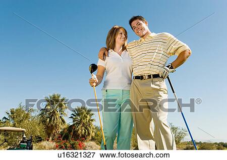 Stock Photo - Couple of golfers embracing on golf course, (portrait), (low angle view). Fotosearch