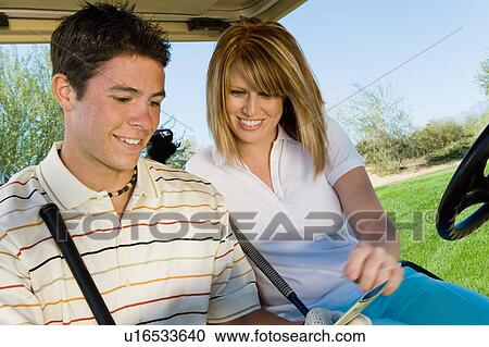Stock Image - Couple of golfers riding in golf cart. Fotosearch