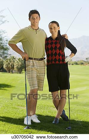 Couple of golfers standing together on golf course, (portrait) View Large Photo Image Stock Image - Couple of golfers standing together on golf course, (portrait). Fotosearch
