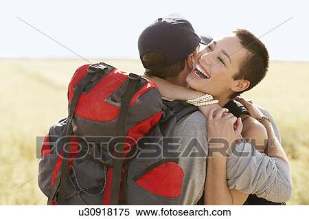 Stock Photography - Couple of hikers hugging in field. Fotosearch