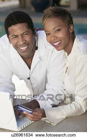 Couple on patio making online credit card purchase, portrait View Large Photo Image Picture - Couple on patio making online credit card purchase, portrait. Fotosearch