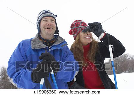 Couple on skis, woman using binoculars, half length View Large Photo Image Stock Image - Couple on skis, woman using binoculars, half length. Fotosearch