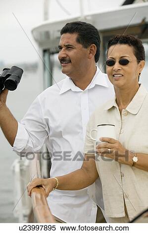 Stock Photography - Couple on yacht, man holding binoculars. Fotosearch