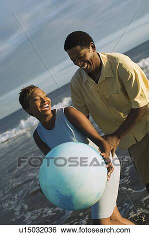 Couple playing with ball at ocean View Large Photo Image Stock Photograph - Couple playing with ball at ocean. Fotosearch