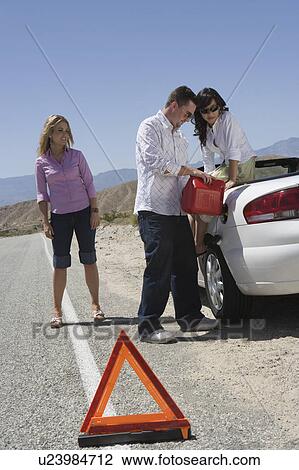 Stock Image - Couple refuel car with friend standing by. Fotosearch