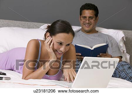 Couple Relaxing on Bed, woman using Laptop View Large Photo Image Stock Photograph - Couple Relaxing on Bed, woman using Laptop. Fotosearch