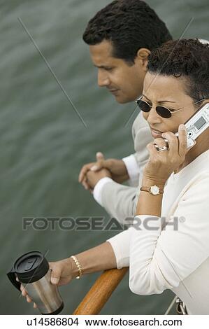 Picture - Couple relaxing on yacht, woman talking on mobile phone, (elevated view). Fotosearch