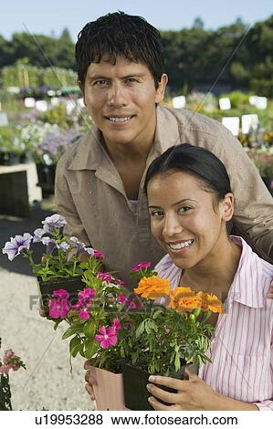 Couple Shopping at Plant Nursery holding flowers, portrait View Large Photo Image Stock Photo - Couple Shopping at Plant Nursery holding flowers, portrait. Fotosearch